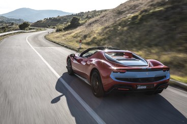 Una Ferrari 296 GTS sfreccia su una strada deserta tra le colline